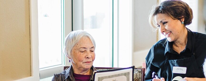 Older woman reading menu and placing order with smiling server