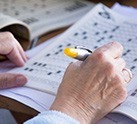 Close-up of hand filling out crossword puzzle with a pen