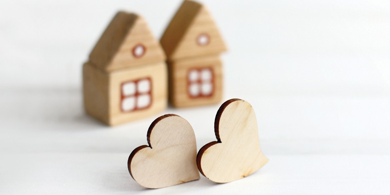 Two small wooden houses with two small wooden hearts