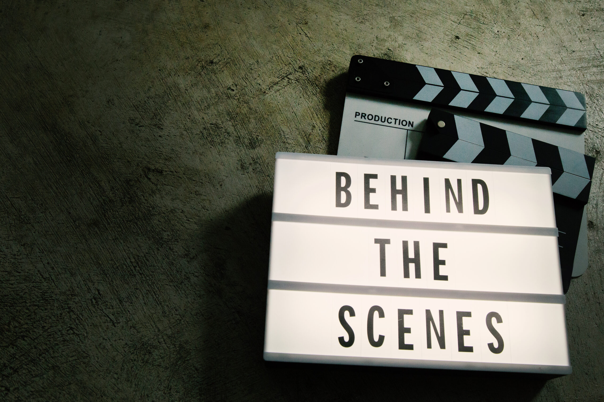 Two clapperboards with a "Behind the Scenes" sign on top of them